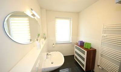 gefliestes Badezimmer mit ebenerdiger Dusche, Waschplatz, WC, beheizten Handtuchhalter und Fön