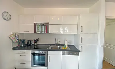 Küchenzeile mit Cerankochfeld, Backofen, Mikrowelle, Geschirrspüler, Kühlschrank mit Gefrierfach, Kaffeemaschine, Wasserkocher, Toaster und anderen praktischen Küchenutensilien