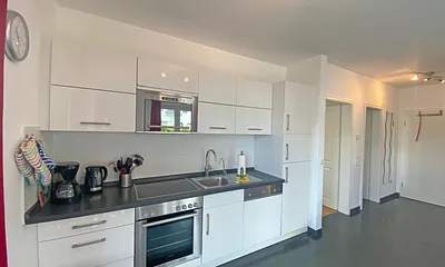 Küchenzeile mit Cerankochfeld, Backofen, Mikrowelle, Geschirrspüler, Kühlschrank mit Gefrierfach, Kaffeemaschine, Wasserkocher, Toaster und anderen praktischen Küchenutensilien