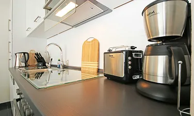 Küchenzeile mit Ceranfeld, Backofen, Geschirrspüler, Kühlschrank mit Gefriermöglichkeit, Mikrowelle, Kaffeemaschine, Wasserkocher, Toaster und diverse Küchenutensilien