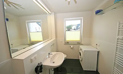 Badezimmer mit Dusche, Waschtisch, großem Spiegel und WC