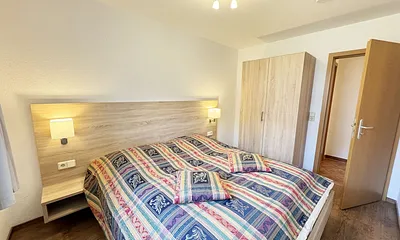 Schlafzimmer mit Doppelbett, Komfortmatratzen (2x 0,90 m x 2,00 m), Nachttischkonsolen, Kleiderschrank und Verdunklungsgardinen