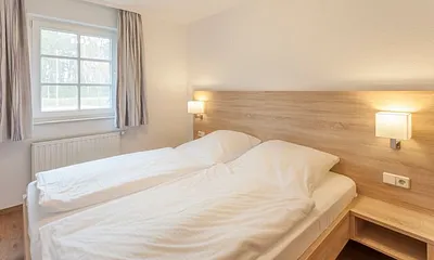 Schlafzimmer mit Doppelbett, Komfortmatratzen (2x 0,90 m x 2,00 m), Nachttischkonsolen, Kleiderschrank und Verdunklungsgardinen