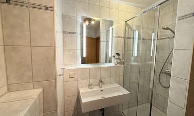 Badezimmer mit Dusche, Waschtisch, Kosmetikspiegel, Fön und WC