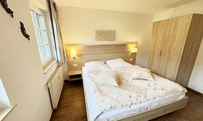 Schlafzimmer hell und modern eingerichtet mit Doppelbett, Komfortmatratzen (2x 0,90 m x 2,00 m), Nachttischkonsolen, Kleiderschrank und Verdunklungsgardinen