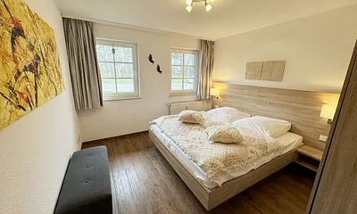 Schlafzimmer hell und modern eingerichtet mit Doppelbett, Komfortmatratzen (2x 0,90 m x 2,00 m), Nachttischkonsolen, Kleiderschrank und Verdunklungsgardinen