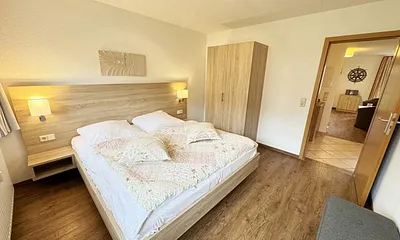 Schlafzimmer hell und modern eingerichtet mit Doppelbett, Komfortmatratzen (2x 0,90 m x 2,00 m), Nachttischkonsolen, Kleiderschrank und Verdunklungsgardinen