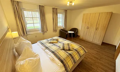 Schlafzimmer hell und modern eingerichtet mit Doppelbett, Komfortmatratzen (2x 0,90 m x 2,00 m), Nachttischkonsolen, Kleiderschrank und Verdunklungsgardinen