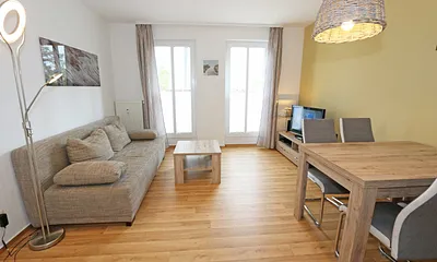 Wohnbereich mit hochwertiger Schlafcouch (1,60 m x 2,00 m, Aufbettungsmöglichkeit für 3/4 Person), Couchtisch, Leselampe, Sideboard mit Smart-TV mit Sky