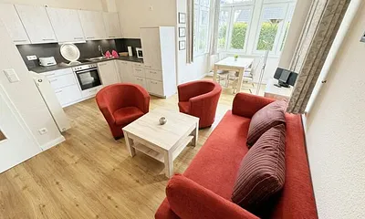 offener Wohnbereich mit Sofa, Sessel, Couchtisch und Sideboard, Flachbild-TV, Blu-Ray-Player und Mini-Stereo-Anlage mit USB-Anschluss