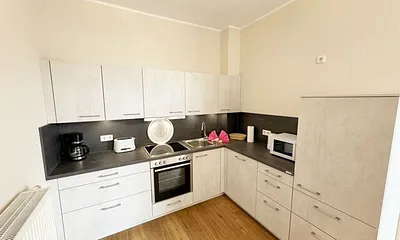 Küchenzeile mit Cerankochfeld, Backofen, Geschirrspüler, Kühlschrank, Gefrierfach, Kaffeemaschine, Mikrowelle, Wasserkocher, Toaster und diversen Küchenutensilien