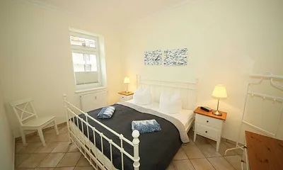 Schlafzimmer mit Doppelbett (1,80 m x 2,00 m), Nachttischablagen, geräumige Kommode und Wandspiegel