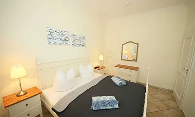 Schlafzimmer mit Doppelbett (1,80 m x 2,00 m), Nachttischablagen, geräumige Kommode und Wandspiegel