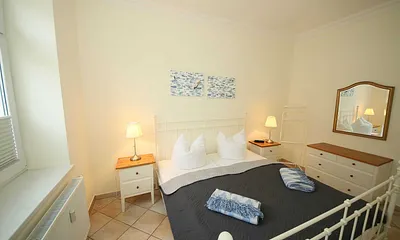 Schlafzimmer mit Doppelbett (1,80 m x 2,00 m), Nachttischablagen, geräumige Kommode und Wandspiegel