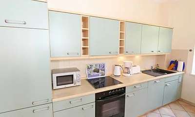 Küchenzeile mit Cerankochfeld, Backofen, Geschirrspüler, Mikrowelle, Kühlschrank, Gefrierfach, Kaffeemaschine, Wasserkocher, Toaster und diversen Küchenutensilien