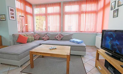 Wohnbereich mit Couch (Ausziehfunktion zum Doppelbett (1,60 m x 2,00 m), Kleiderschrank, Sessel, Couchtisch, kleinem Beistelltisch, Flachbild-TV, DVD-Player sowie Mini-Stereo-Anlage mit USB-Anschluss