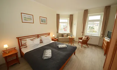 Schlafzimmer mit Doppelbett (1,80 m x 2,00 m), großem Kleiderschrank, Nachttischablagen, Kommode mit Smart-TV und komfortabler Leseecke mit kleiner Bücherauswahl