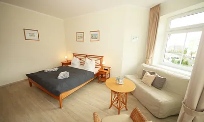 Schlafzimmer mit Doppelbett (1,80 m x 2,00 m), großem Kleiderschrank, Nachttischablagen, Kommode mit Smart-TV und komfortabler Leseecke mit kleiner Bücherauswahl