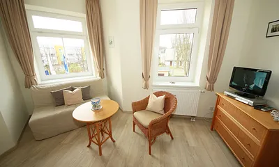 Schlafzimmer mit Doppelbett (1,80 m x 2,00 m), großem Kleiderschrank, Nachttischablagen, Kommode mit Smart-TV und komfortabler Leseecke mit kleiner Bücherauswahl