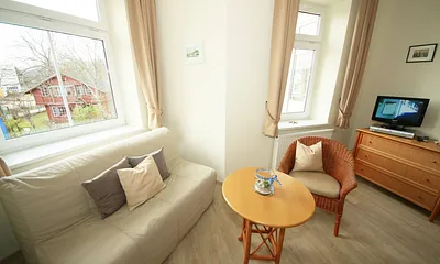 Schlafzimmer mit Doppelbett (1,80 m x 2,00 m), großem Kleiderschrank, Nachttischablagen, Kommode mit Smart-TV und komfortabler Leseecke mit kleiner Bücherauswahl