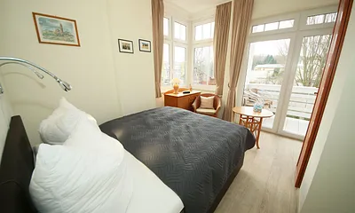 Schlafzimmer mit Boxspringbett (1,60 m x 2,00 m), kleinem Kleiderschrank, Kommode und Tisch mit 1 Sessel