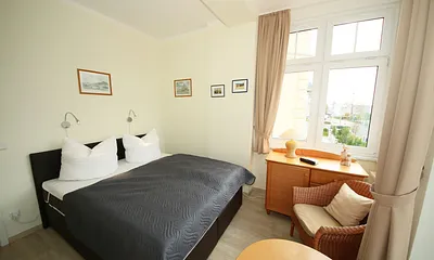 Schlafzimmer mit Boxspringbett (1,60 m x 2,00 m), kleinem Kleiderschrank, Kommode und Tisch mit 1 Sessel