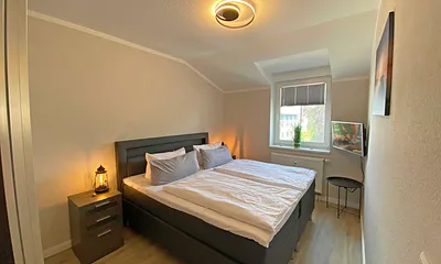 Schlafzimmer mit Boxspringbett (1,80 m x 2,00 m), Nachtischablagen, Kleiderschrank und Smart-TV 