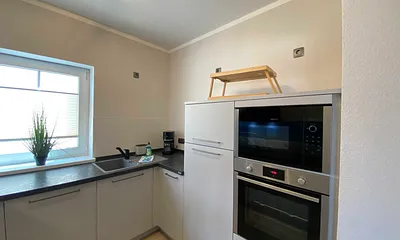 moderne Küchenzeile mit Geschirrspüler, Toaster, Wasserkocher, Kaffeemaschine, 4 Zonen-Kochfeld, Backofen, integrierte Mikrowelle, Kühl-Gefrierkombination und hochwertigen Granitarbeitsflächen