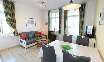 Wohnzimmer mit Sitzecke (Schlafcouch für 3./4. Person 1,50 m x 2,00 m), Smart-TV (81 cm), Leselampe, Blu-Ray-Player, DAB Radio und kleiner Anrichte