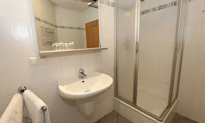Badezimmer mit Dusche (flacher Einstieg), WC, Waschtisch und Fön 