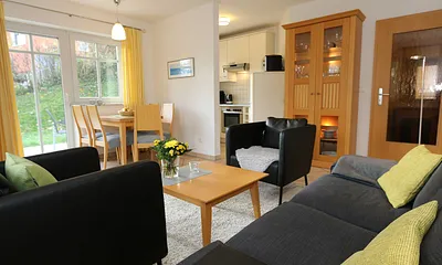 Wohnbereich mit Sofa, Sessel, Couchtisch, Vitrine, Leselampe, Flatscreen-TV mit DVD-Player, Stereoanlage mit CD und einer kleinen Auswahl an Gesellschaftsspielen 