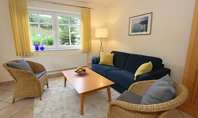 Wohnbereich mit Sofa, Sessel, Couchtisch, Vitrine, Leselampe, Flatscreen-TV mit DVD-Player, Stereoanlage mit CD und eine kleine Auswahl an Gesellschaftsspielen