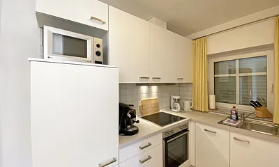 helle Küchenzeile mit Ceranfeld, Backofen, Geschirrspüler, Mikrowelle, Kühlschrank mit Gefrierfach, Kaffeemaschine, Senseo Kaffeeautomat, Toaster, Wasserkocher und diverse Küchenutensilien