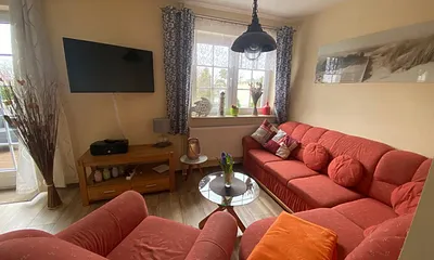 Wohnzimmer mit Fernseher und Sitzmöglichkeiten