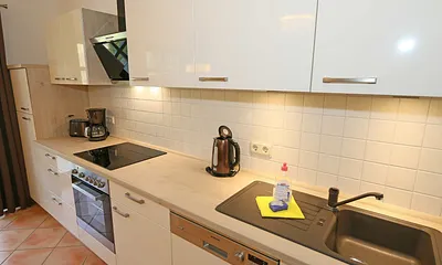 Küchenzeile mit Kühl-Gefrierkombination, Geschirrspüler, Backofen mit Ceran-Kochfeld, Kaffeemaschine, Toaster, Wasserkocher sowie diverse Küchenutensilien