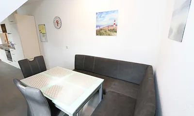 Essbereich mit zwei Stühle, Glastisch sowie eine Sitzecke