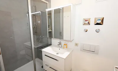 Badezimmer mit komfortabler Dusche (1,20 m x 0,80 m) mit Glasschiebetür, WC, Waschtisch, Kosmetikspiegel, Unterschrank, Spiegelschrank, Kosmetikspiegel sowie ein Fön