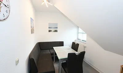 Essbereich mit zwei Stühle, Glastisch sowie eine Sitzecke