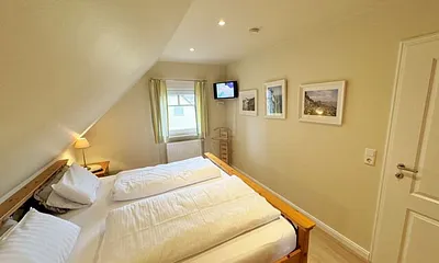 Schlafzimmer mit Doppelbett (2,00 m x 2,00 m), Nachttischkonsolen, Kleiderschrank und einer Kommode mit Flachbild-TV