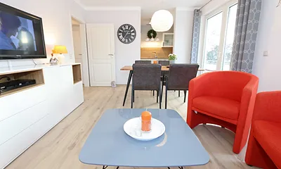 Wohnzimmer mit Schlafcouch (1,60 m x 2,00 m, Aufbettung für 2 Personen), zwei Sessel, Couchtisch, Smart-TV, DVD-Player, Radio mit CD-Player sowie verschiedene Lektüren für Leseratten