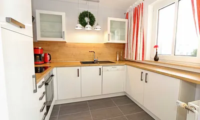 moderne Küchenzeile mit Ceranfeld, Backofen, Kühlschrank mit Eisfach, Geschirrspüler, Mikrowelle, Wasserkocher, Toaster, Kaffeemaschine und diverse Kochutensilien