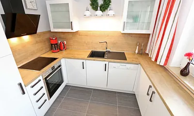 moderne Küchenzeile mit Ceranfeld, Backofen, Kühlschrank mit Eisfach, Geschirrspüler, Mikrowelle, Wasserkocher, Toaster, Kaffeemaschine und diverse Kochutensilien