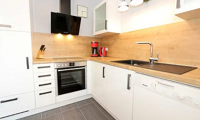 moderne Küchenzeile mit Ceranfeld, Backofen, Kühlschrank mit Eisfach, Geschirrspüler, Mikrowelle, Wasserkocher, Toaster, Kaffeemaschine und diverse Kochutensilien