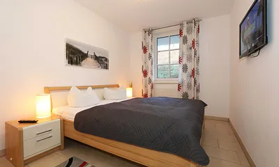 Schlafzimmer mit Doppelbett und TV