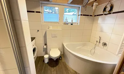 Bad mit Dusche, Waschplatz, WC, Waschmaschine, Kosmetikspiegel, Fön, Wellnesswanne und Sauna