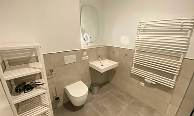 innenliegendes Bad mit einem Waschtisch, beheiztem und beleuchtetem Spiegel, Handtuchheizung, Fön, Kosmetikspiegel, WC sowie eine große ebenerdige Klarglas-Dusche mit Regenduschkopf