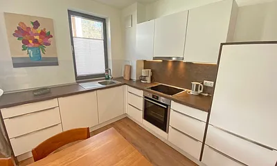 Küchenzeile mit Backofen, Kühlschrank mit Gefrierfach, Spülmaschine, Cerankochfeld, Wasserkocher, Kaffeemaschine, Espressokocher, Toaster sowie einen massiven Holzesstisch mit lederbezogene Essstühle