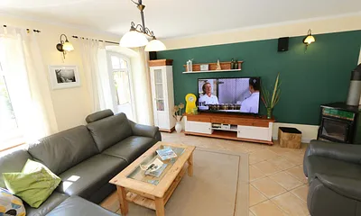 gemütlicher Wohnbereich mit einer großen Couchecke, Couchtisch, Leselampe, Sideboard, Flachbild-TV und Mini-Stereo-Anlage