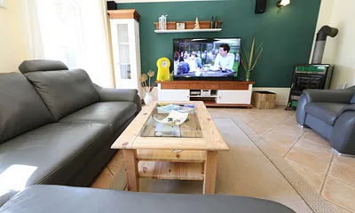 gemütlicher Wohnbereich mit einer großen Couchecke, Couchtisch, Leselampe, Sideboard, Flachbild-TV und Mini-Stereo-Anlage