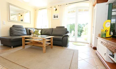 gemütlicher Wohnbereich mit einer großen Couchecke, Couchtisch, Leselampe, Sideboard, Flachbild-TV und Mini-Stereo-Anlage